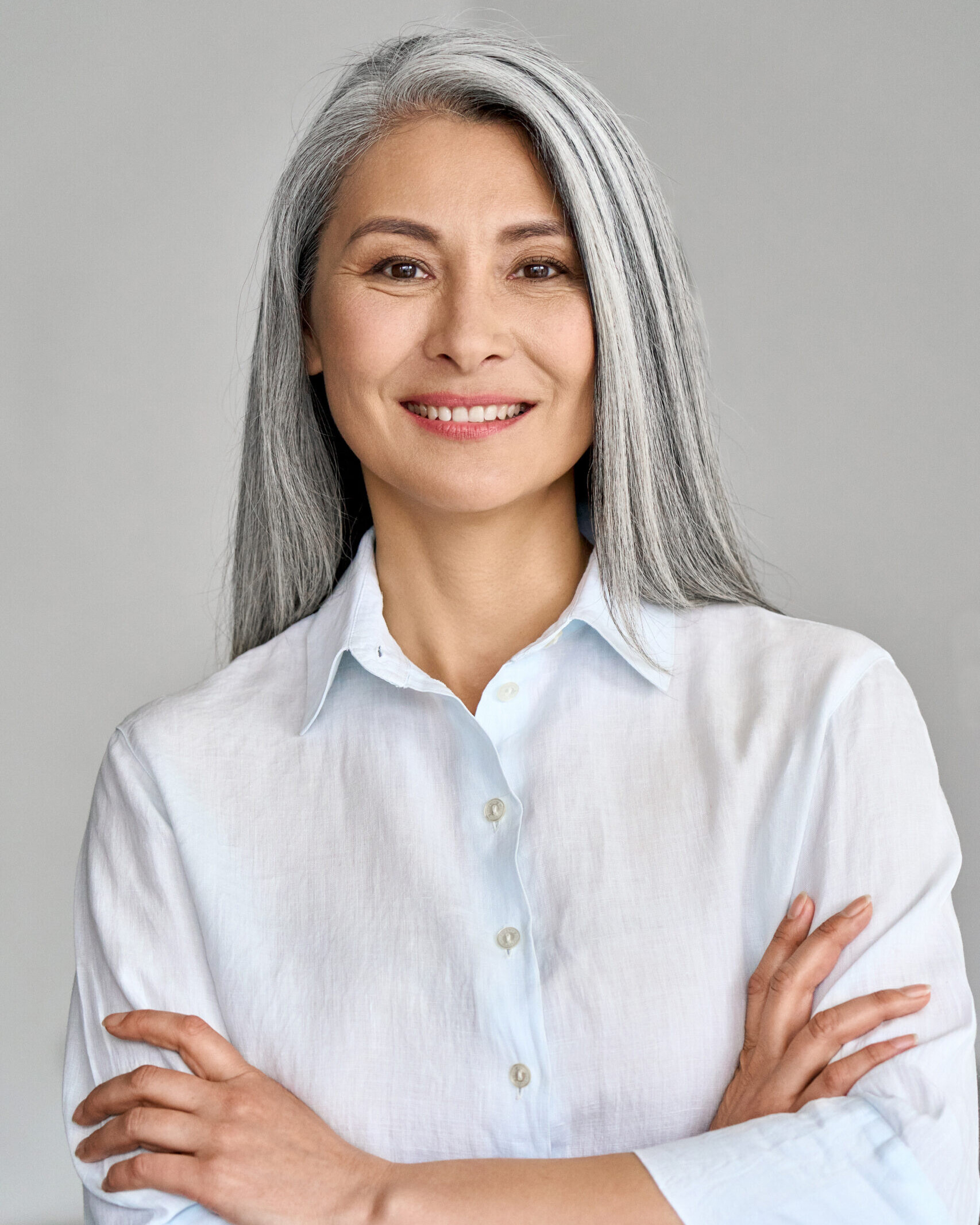 Vertical portrait of mature 50 years Asian business woman on grey background.